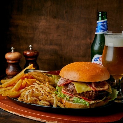 Burger with fries and beer on a wooden table.
