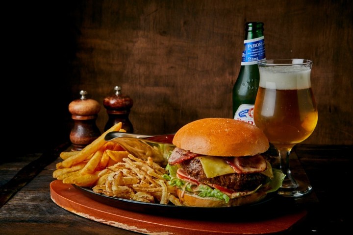 Burger with fries and beer on a wooden table.