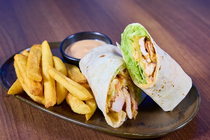 Chicken wrap with fries and dipping sauce on a plate.