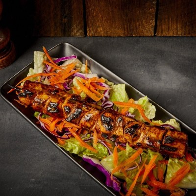 Grilled kebab skewer on salad with lettuce and shredded carrots.